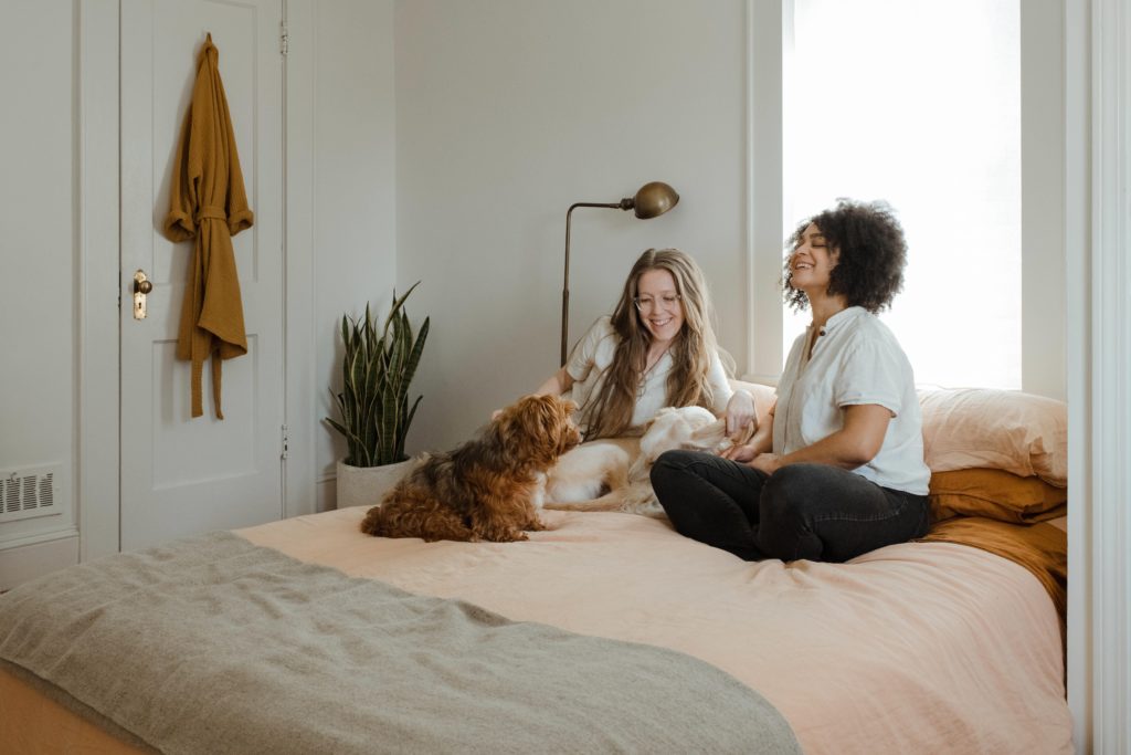 Celebrating childfree women | 2 women and a dog chatting on a bed